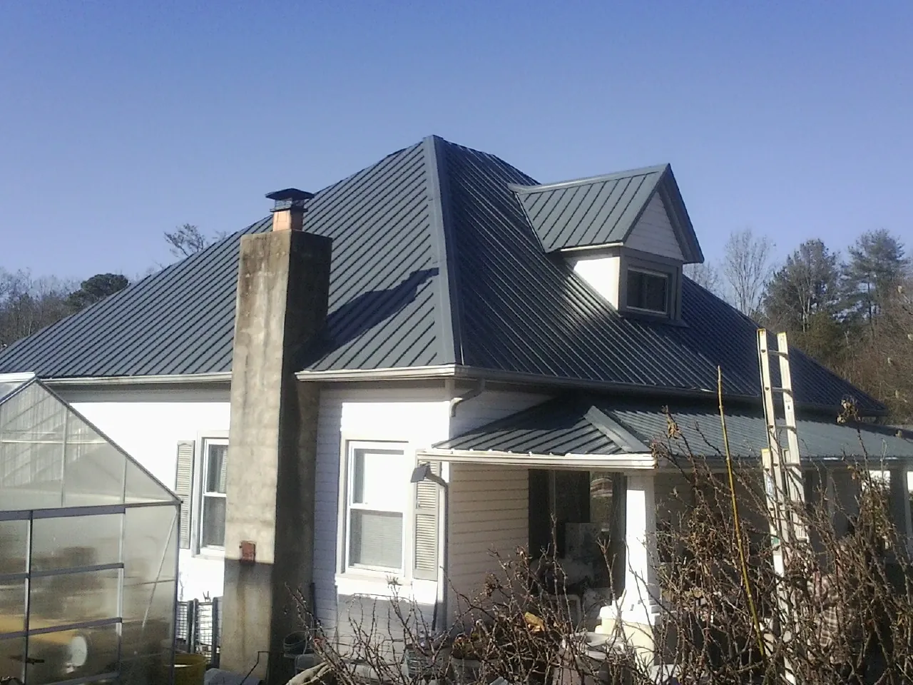 Dark blue standing seam metal roof on a white farmhouse with dormer — Slate & Tile Roof Repair by Roofing Brothers in Slingerlands