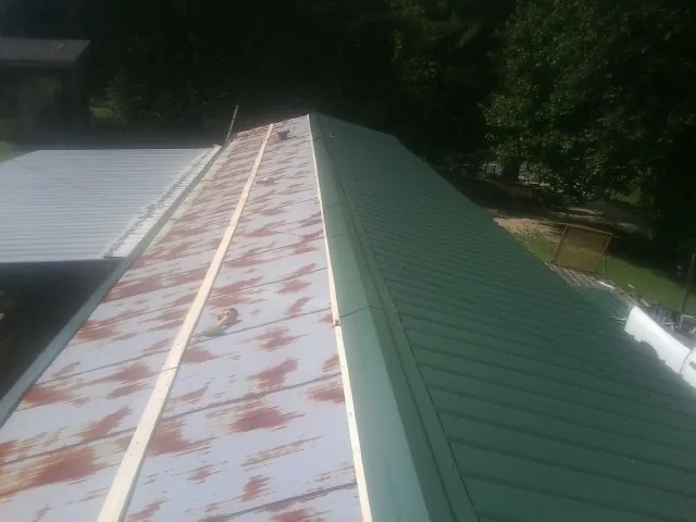 Old rusted panels beside newly installed green metal roofing — Wind Damage Roof Repair by Roofing Brothers in Slingerlands
