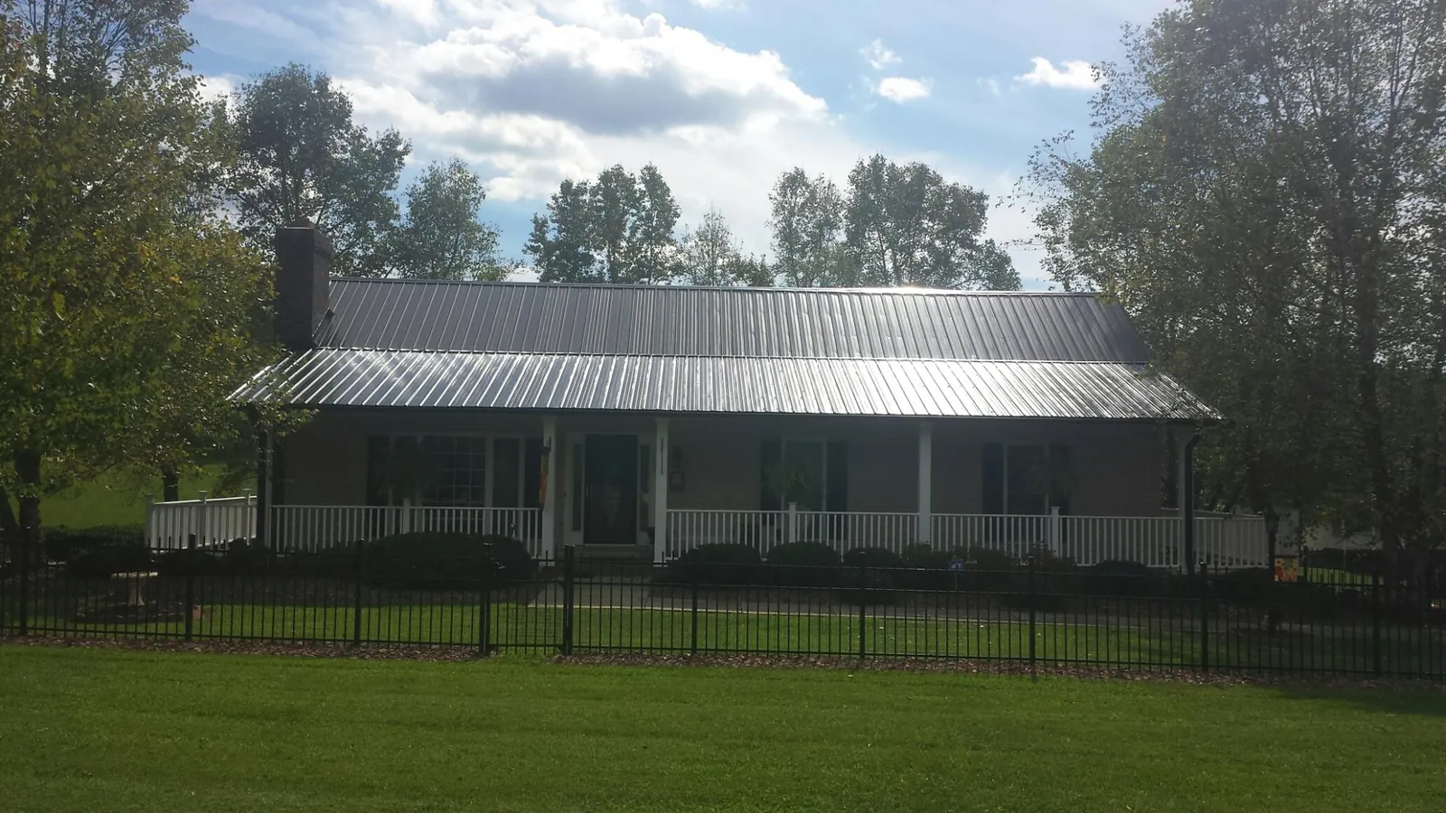 Gray metal roof on a brick ranch with a full width front porch — Gutter Guard Installation work by our crew in Slingerlands